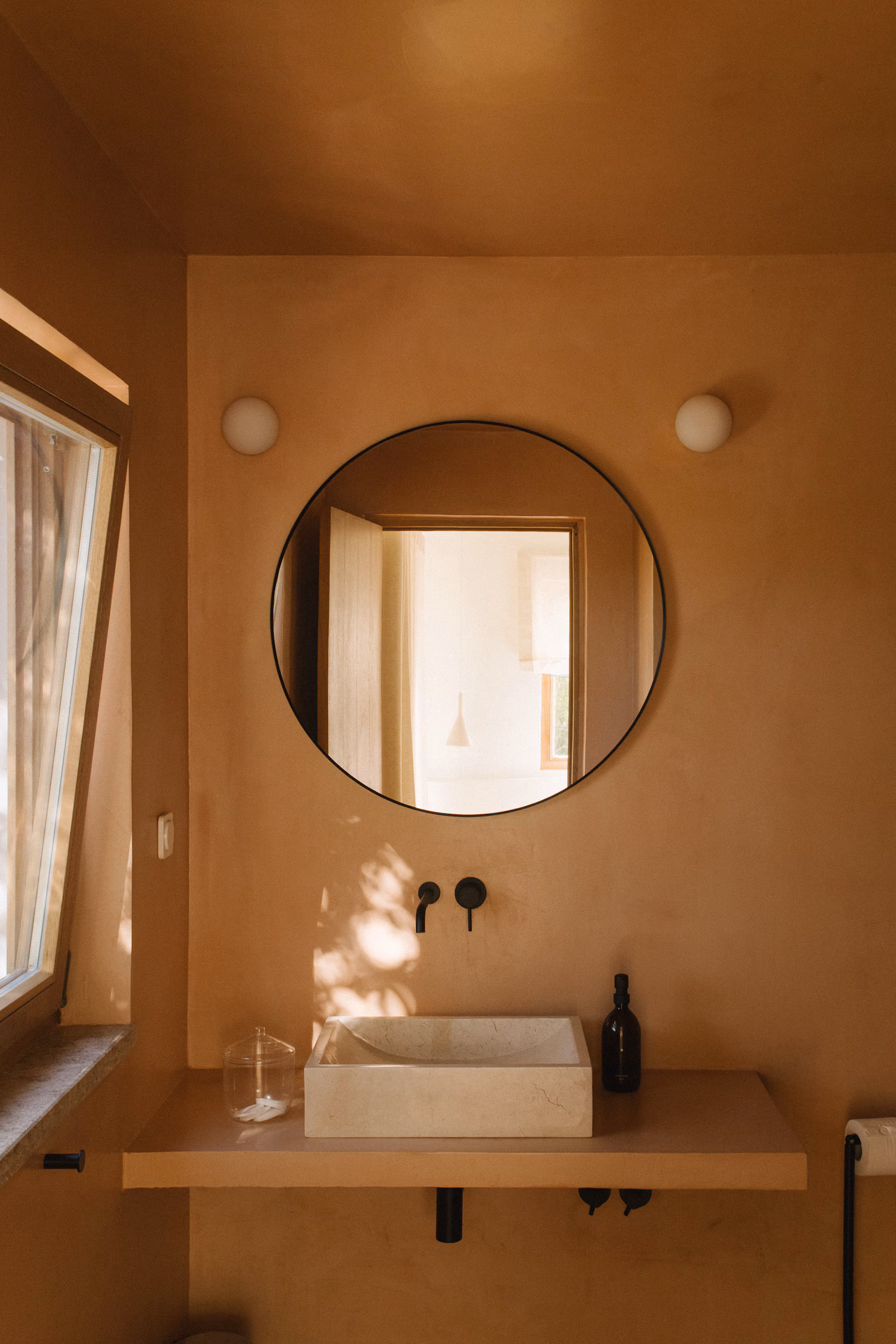 Terracotta-walled bathroom with round mirror