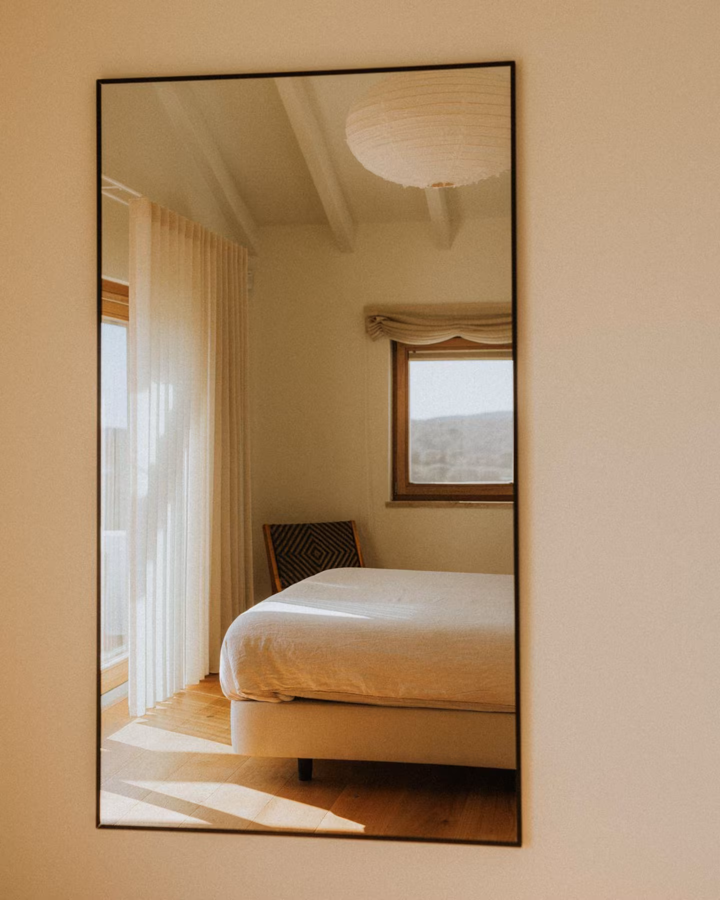 Bedroom reflected in a tall mirror